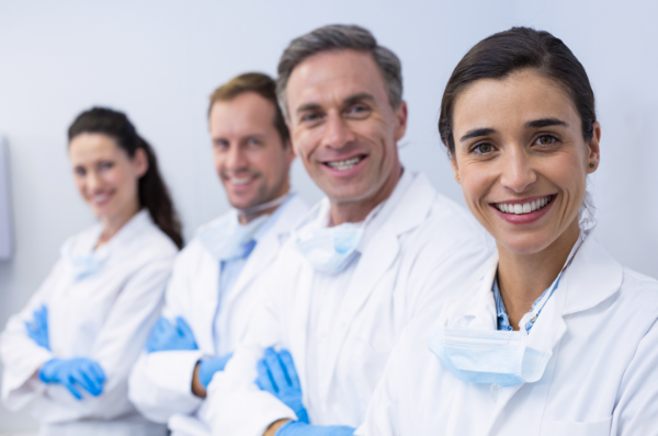 Four dental professionals in scrubs smiling