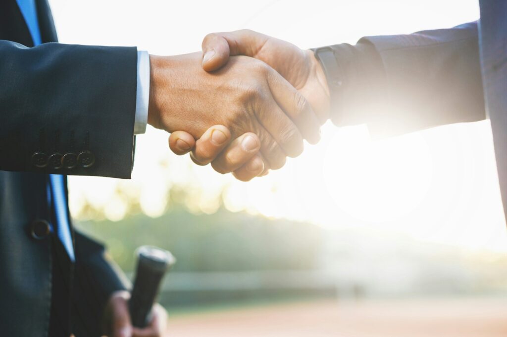 Close-up of two hands shaking, symbolizing a successful dental practice transition facilitated by Legacy Practice Transitions