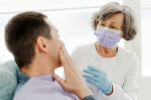 An older dentist examining a patient, symbolizing the transition to retirement and the opportunity to sell their dental practice with the guidance of Legacy Practice Transitions.