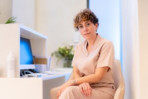 Dentist sitting at a computer desk, confidently looking at the camera, symbolizing the start of a successful dental practice purchase with Legacy Practice Transitions.