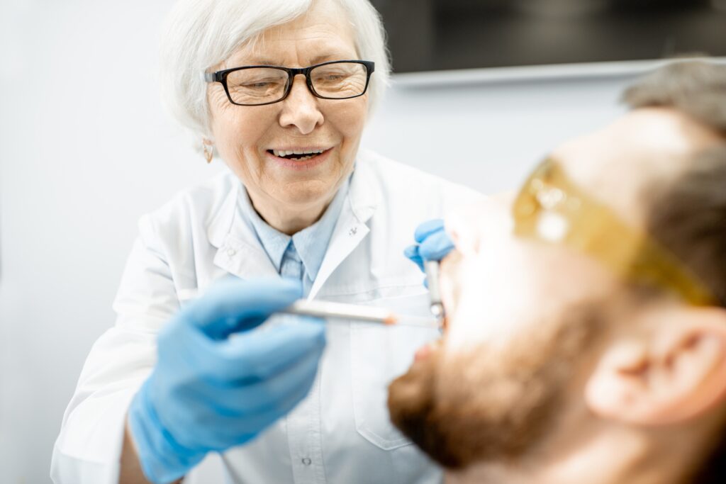 Senior female dentist treating a patient, symbolizing retirement and transition planning services offered by Legacy Practice Transitions for dental professionals.
