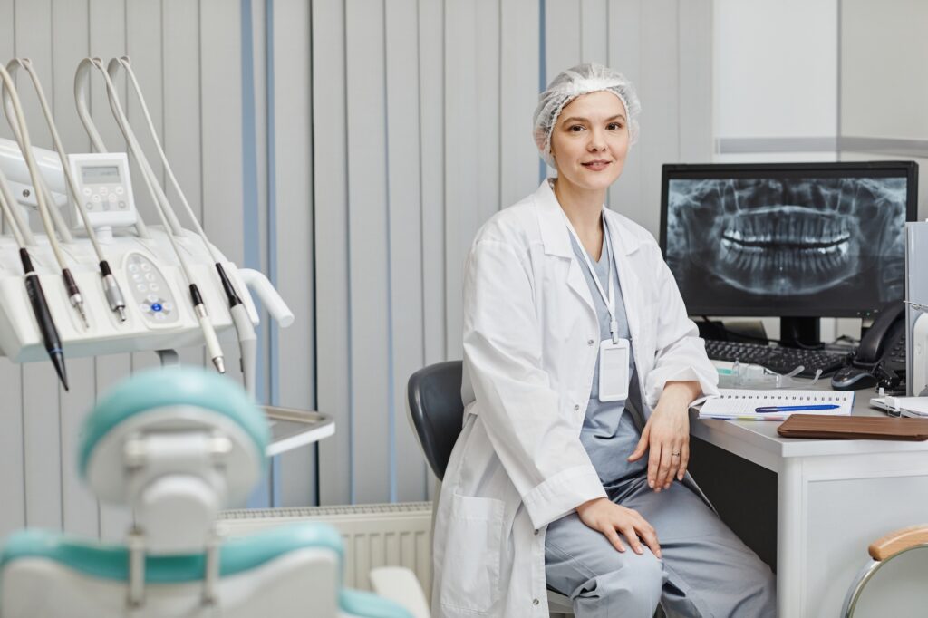 Dentist in modern office with dental chair and X-ray display, representing factors that influence dental practice value.